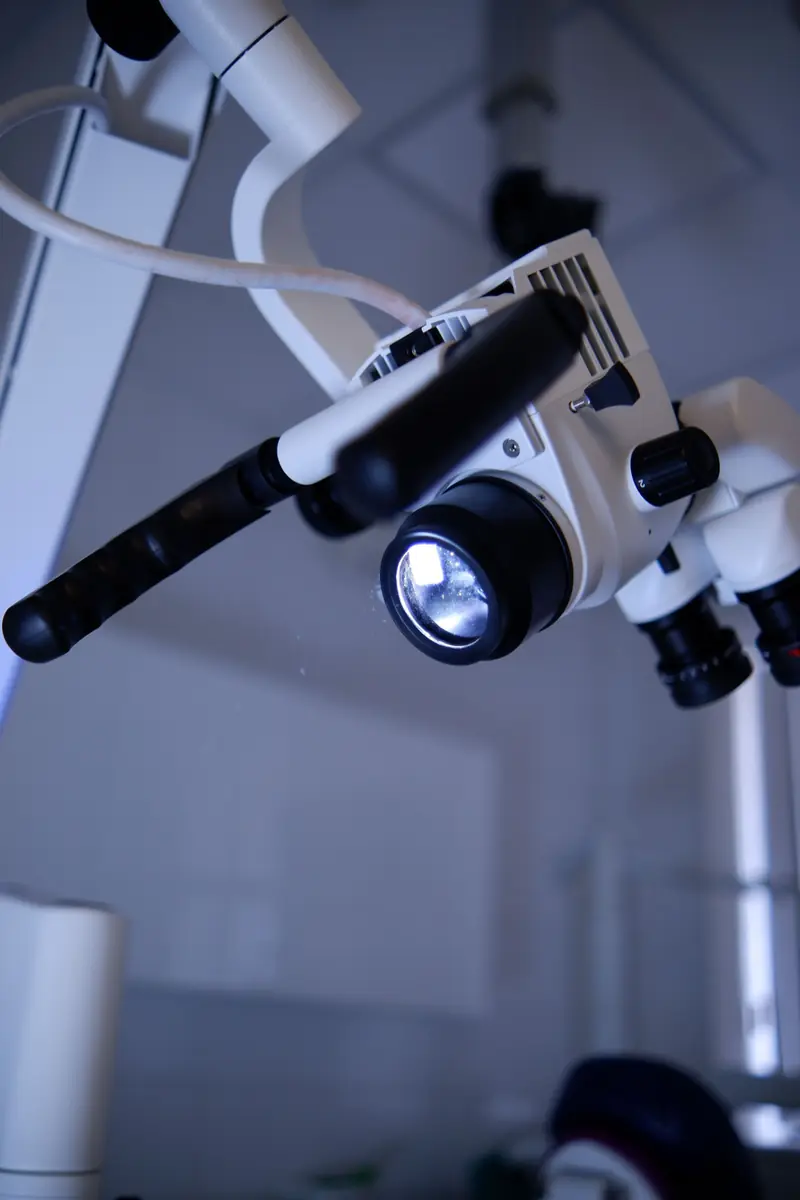 Microscopio operatorio con la luce accesa, sospeso sul braccio articolato.