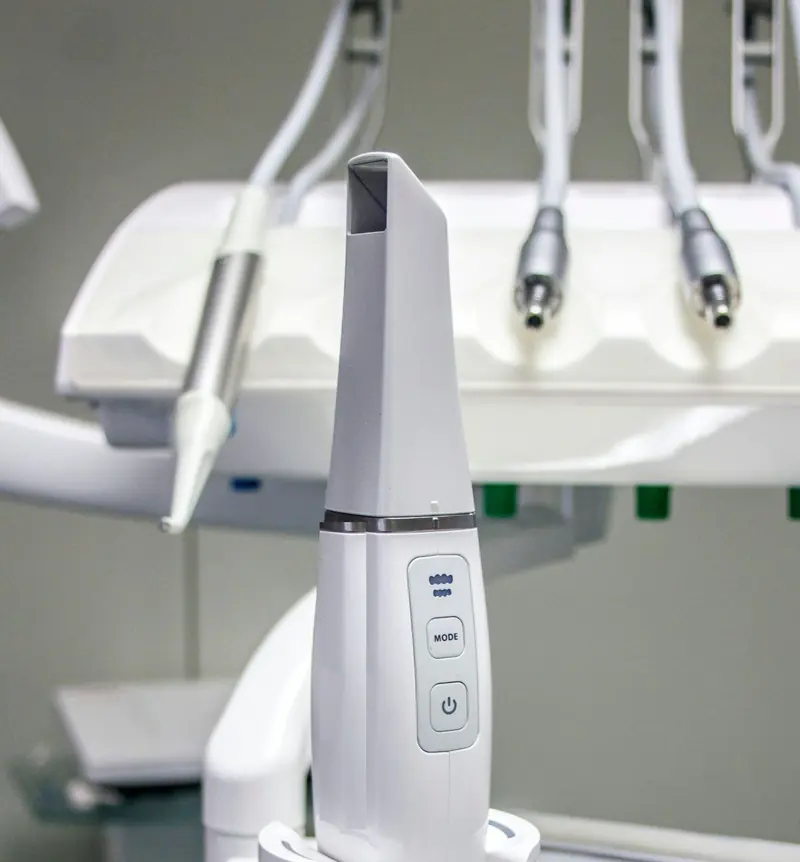 Scanner intraorale appoggiato sulla sua base, davanti agli strumenti del riunito.