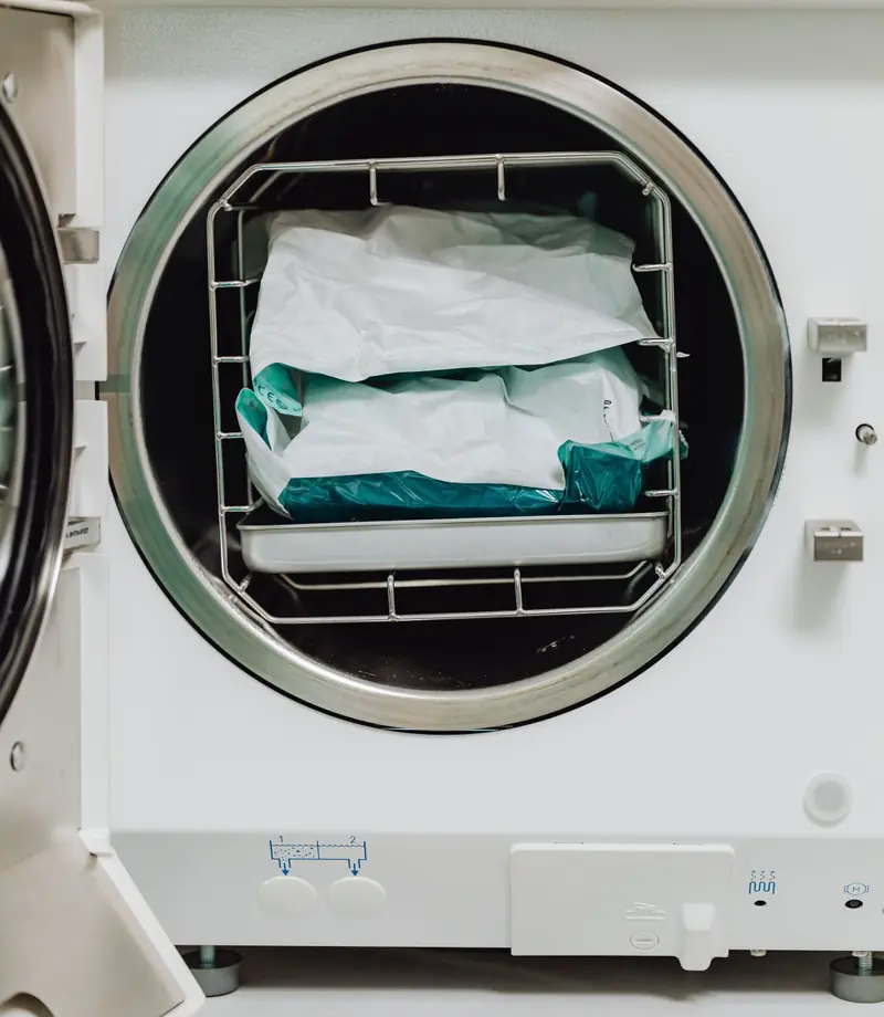 Autoclave aperta con le buste di strumenti sterilizzati sul cestello.