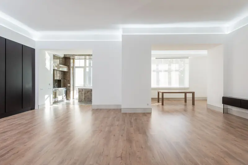 Appartamento consegnato vuoto: pareti bianche, aperture ad arco ribassato tra gli ambienti, pavimento in laminato e luce perimetrale nel controsoffitto.