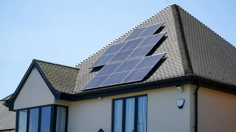 Pannelli fotovoltaici sulla falda di una villetta con il tetto scuro e le pareti color sabbia.