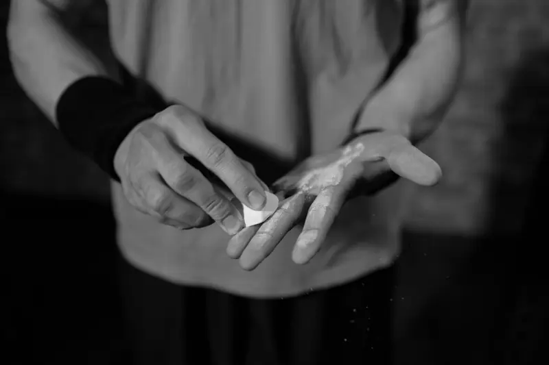 Due mani si passano la magnesite prima di un esercizio con il bilanciere.