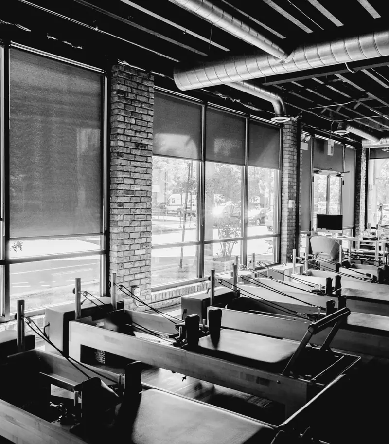 Una sala corsi con le vetrate su tre lati e gli attrezzi da pilates in fila.
