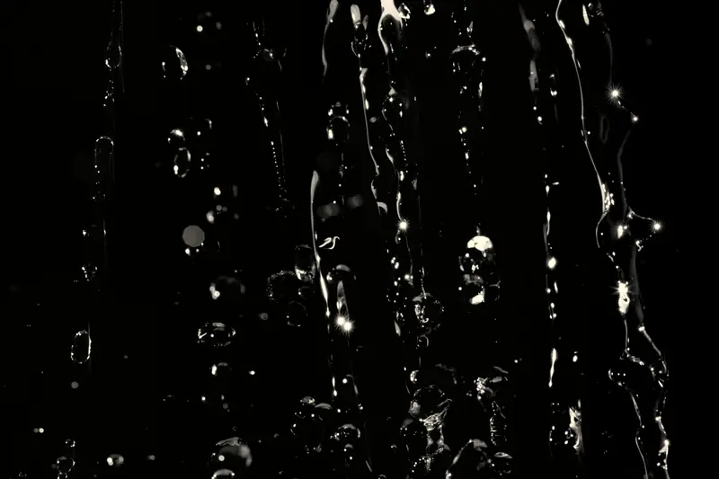 Gocce d'acqua che cadono su un fondo scuro.